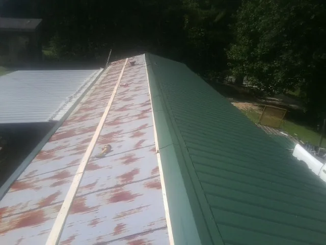 Old rusted panels beside newly installed green metal roofing — Wind Damage Roof Repair by Roofing Brothers in Weatogue