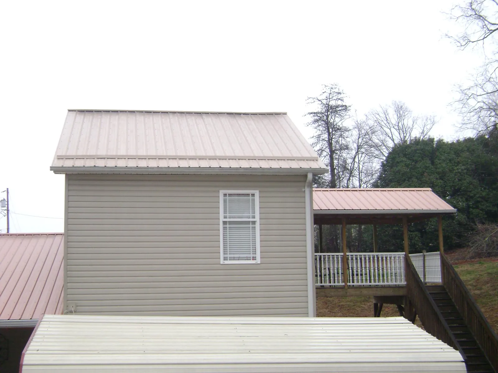 Tan metal roofs on a two story addition and attached porch, from a Roof Replacement job in Weatogue