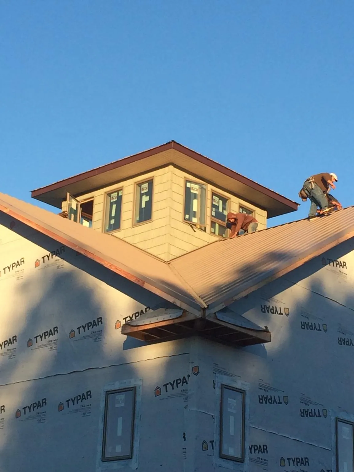 Roofers working around a rooftop cupola on a new metal roof at sunset — Roof Waterproofing in Weatogue by Roofing Brothers